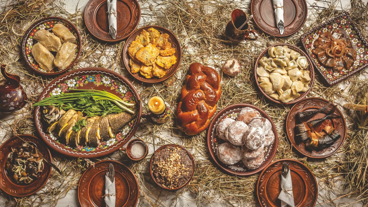 A holiday table of Belarusian dishes laid out on hay, a photograph from the Holiday Menus chapter of The Belarusian Cookbook