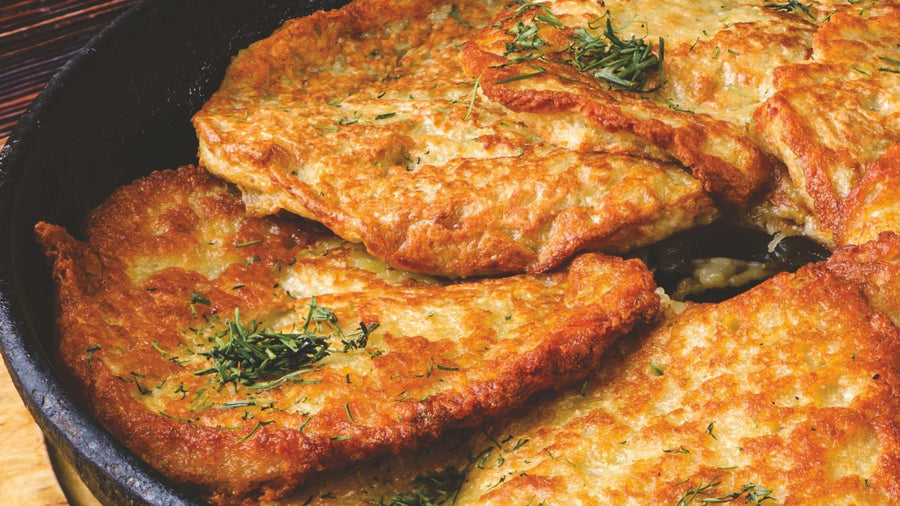 Draniki, Belarusian potato pancakes, in a cast-iron pan, a photograph from The Belarusian Cookbook