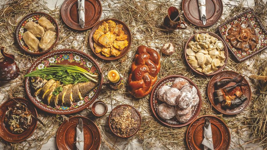 A holiday table of Belarusian dishes laid out on hay, a photograph from the Holiday Menus chapter of The Belarusian Cookbook